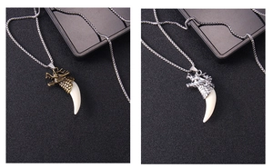 Detailed view of silver and bronze dragon head wolf tooth pendants on metal box chains