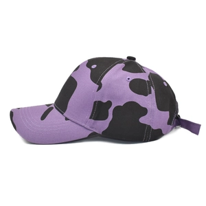 Detail showing the purple cow print pattern and texture on cotton baseball cap