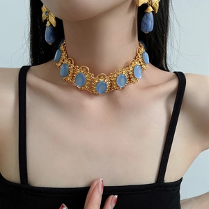 Detailed view of model wearing vintage golden filigree necklace and blue gemstone earrings