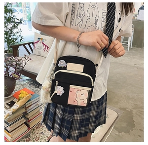 Détail du sac bandoulière en toile noire avec écusson ours et poche transparente stylée