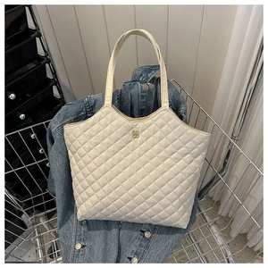Détail d'un sac fourre-tout matelassé crème avec logo floral doré dans un panier
