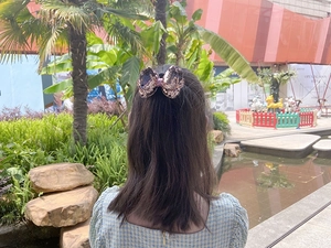 Outdoor shot of a girl wearing a rose gold sequin bow hair clip in her ponytail