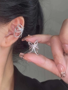 Detailed close-up of a silver bow-shaped ear cuff featuring micro-paved sparkling zircons