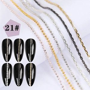Detail of assorted metal nail art chains in gold and silver on black nails