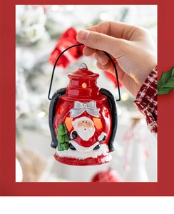 Detail of hand holding a red ceramic Santa lantern with warm LED light and festive relief