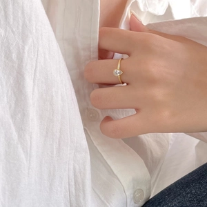Close-up of minimalist gold sterling silver ring with a pear-cut zircon on a model hand