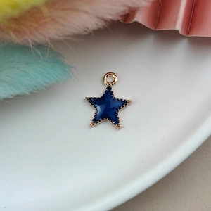 Macro shot of gold-plated blue enamel star pendant charm with hanging loop detail