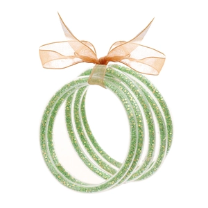 Dettaglio di cinque braccialetti glitter verdi con un fiocco in organza arancio rosa