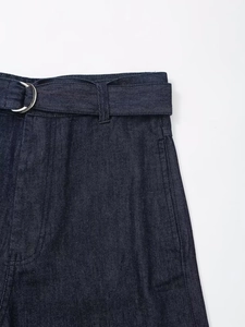 Détail de la taille d'un jean bleu foncé avec ceinture réglable et boucle en D argentée