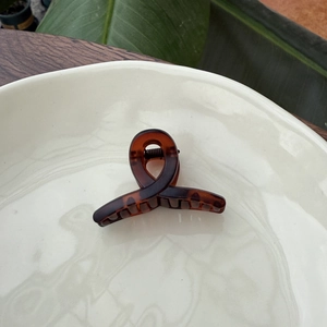 Detailed view of a brown tortoiseshell hair claw clip placed on a white ceramic dish