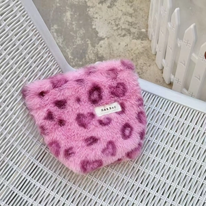 Close-up of pink leopard heart plush texture and H&R BAG label on travel pouch