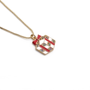 Gold plated Christmas gift box necklace with white enamel and red bow on white background
