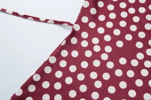 Close-up of the burgundy polka dot fabric texture and side tie detail on the dress