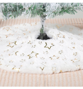 Detail of plush white Christmas tree skirt with gold foil star patterns and soft texture