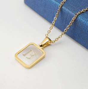 Macro shot of 18K gold plated square pendant with white shell inlay and letter B