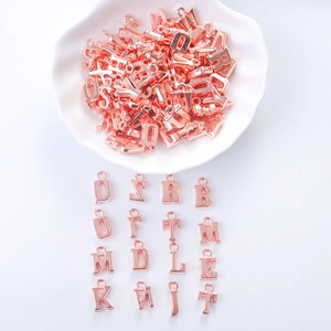Detail of rose gold alphabet letter charms arranged on a white scalloped plate and background