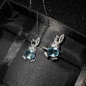 Close-up of rabbit jewelry set with sky blue oval gemstone on black silk background