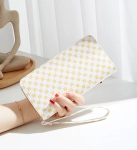Detailed view of a white long floral purse with yellow geometric prints and wrist strap