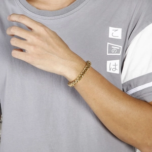 Détail d'un bracelet tressé en acier inoxydable doré pour homme porté au poignet