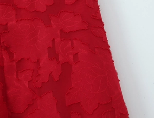 Gros plan sur le tissu jacquard rose rouge montrant la texture florale détaillée