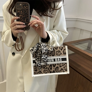 Fashionable leopard print tote bag with beige handles and silk scarf detail on display