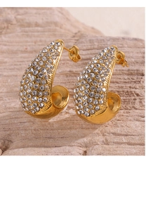 Macro view of C-shaped half-hoop gold earrings with sparkling pave-set crystal rhinestones