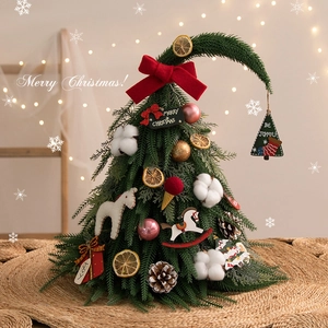 Mini DIY green Christmas tree with red bow, dried lemon and cotton on a straw mat