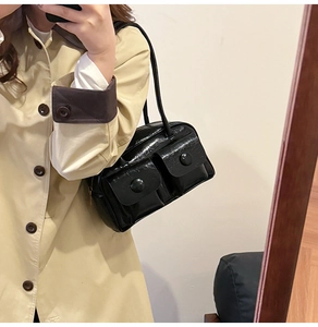 Mirror selfie showing a black glossy messenger bag with dual pockets on a model