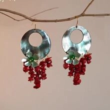 Dettaglio di orecchini boho con motivi floreali e nappe di perline in corallo rosso