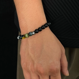 Close-up of beaded bracelet with black obsidian and colorful tiger eye stones on wrist