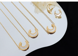 Macro detail of gold-plated horseshoe necklaces and earrings with white pearl inlay