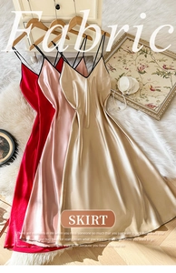 Detail view of satin nightgown fabrics in red, pink, and gold on soft white rug