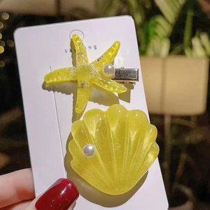 Detail of yellow starfish and shell hair clips with pearls on a silver duckbill base