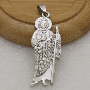 Macro view of silver saint pendant with micro-pave crystals on textured white surface