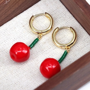 Sweet red cherry drop earrings with gold hoops on a minimalist linen jewelry display