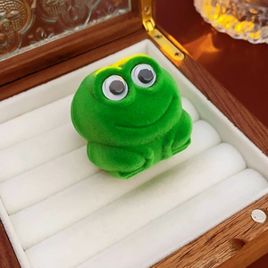 Detail of cute green flocked frog jewelry box inside a wooden case with white lining