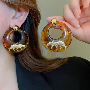 Macro detail of amber resin hoop earring with golden leopard relief and sphere hook