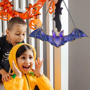 Kids reacting to a hanging purple acrylic bat ornament in a Halloween setting