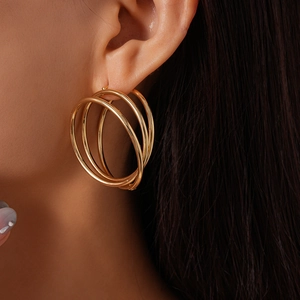 Close-up of golden triple-layered hollow circular earrings on a fashion model