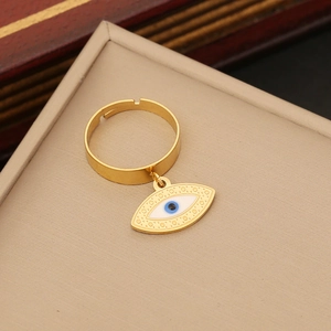 Macro shot of gold-plated evil eye ring with blue enamel on a beige jewelry display