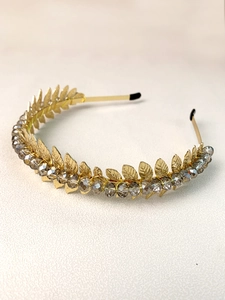 Detail of golden leaf headband with grey crystals on a textured cream background