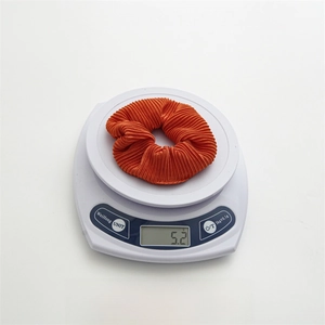 Detail shot of orange pleated scrunchie on electronic scale showing 5.2g weight