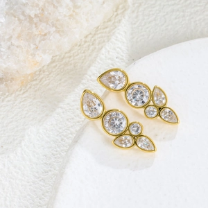 Detailed view of teardrop zircon earrings in gold finish on white crystal background