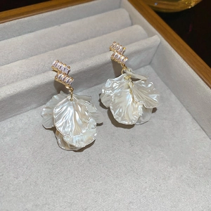 Close-up of shell petal earrings with gold geometric design and sparkling cubic zirconia