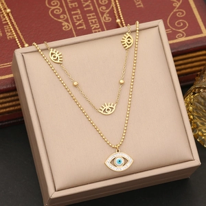 Detail of gold layered necklace with blue enamel evil eye pendants on a jewelry box