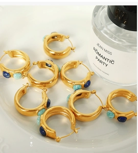 Detail of gold-plated C-shaped earrings with inlaid lapis lazuli and green turquoise stones