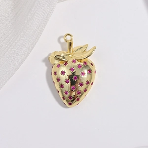 Detailed macro view of a golden strawberry pendant with pink gemstones on white surface