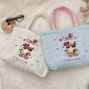 Détail de sacs matelassés avec broderie de chien sur un tapis en peluche blanc