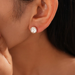 Close-up of a silver-tone woven texture circular stud earring on model's ear