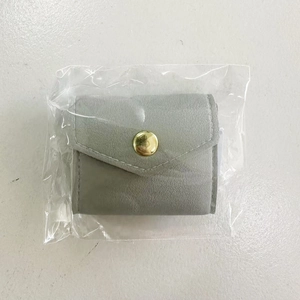 Detail of gray soft leather jewelry pouch with golden snap button in transparent packaging